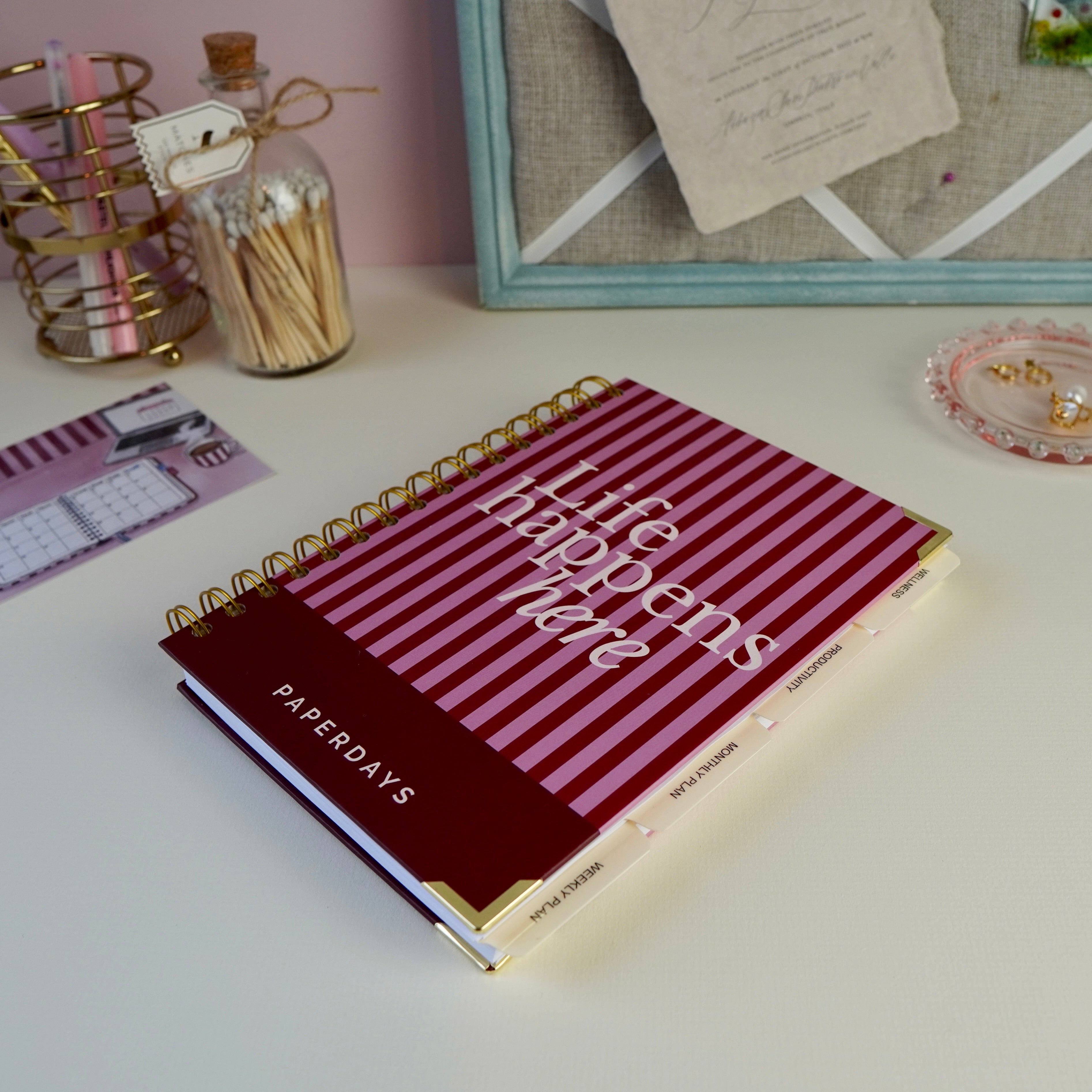 Gratitude journal, wellness journal and moon-and-stars journal by PaperDays in soft pastels, photographed with a candle.